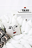 Weisses Kissen-Sofa mit Dekokissen, im Hintergrund Taxi-Leuchte als Tischlampe