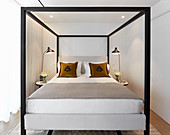 Four-poster bed with black cubist frame in small room