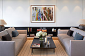 Two grey sofas facing one another in front of colourful abstract painting