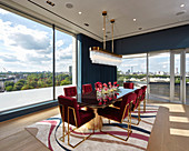 Red velvet chairs with gilt frames in dining room with panoramic view of city