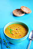 Currysuppe in einer rustikalen Schale und getoastetes Brötchen im Hintergrund