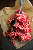 Fresh minced meat with a spoon on a piece of paper (close-up)