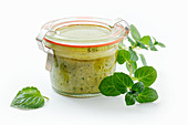 Homemade mint tapenade in a jar against a white background