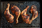 Roasted chicken legs on a baking tray (seen from above)