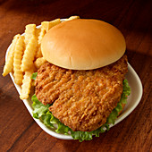 Breaded fried chicken sandwich with lettuce and french fried potatoes