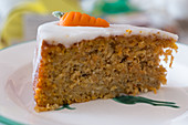 A slice of carrot cake with icing and marzipan carrots