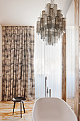 Bathroom with marble tiled floor and Murano glass chandelier above the bathtub