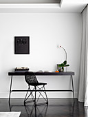Small workplace with black table and designer chair on white wall