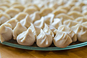 Close up of freshly home made chinese dumplings on a glass plate and wooden table