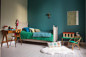Bed, desk and chair in child's bedroom with turquoise wall
