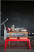 Red bench, wooden table and sofa against wall painted with chalkboard paint