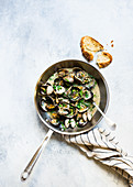 Mussels in garlic and white wine sauce served in a pan with bread