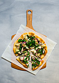 Vegetarian pizza with artichokes, broccolini and shiitake on a wooden board