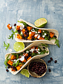 Soft taco shells with sweet potatoes, beans and rocket