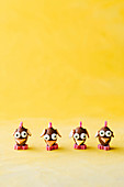 Comical chicks made of chocolate easter eggs against a yellow background