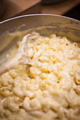 A cook preparing pasta and cheese sauce for making macaroni cheese