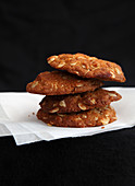A stack of oatmeal cookies on paper against a black background