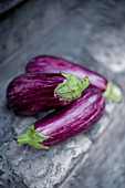 Three fresh eggplants on a stone background