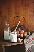 Fresh eggs in a wire basket, a bottle of milk, and a jar of sugar