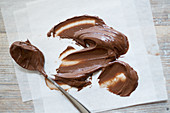 Chocolate cream on a spoon and a sheet of paper