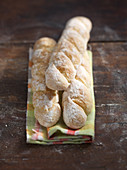 Small homemade baguettes on a cloth against a wooden background