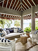 Outdoor furniture with blue and white patterned cushions on a covered terrace with sea views