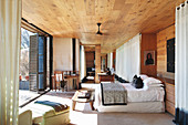 Doppelbett im Schlafzimmer mit Holzverkleidung und Terrassenzugang