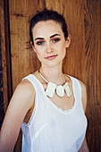 A young brunette woman wearing a white top and a chunky necklace