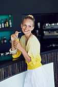 Blonde Frau in gelber Bluse an der Bar