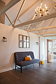 Couch against half-height partition in converted stable with exposed wooden roof structure