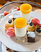 Petit fours, macaroons and layered desserts for tea time on a cake stand