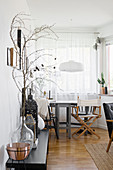 Demijohn and lantern on wooden bench with dining area next to window in background