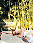 A young woman wearing a bathing suit lying by the side of a pool