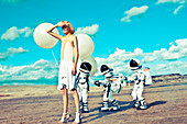 Futuristic Fashion: a blonde woman outside with balloons and children in astronaut costumes