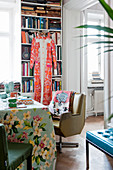 Retro armchair at table with floral tablecloth in front of bookcase