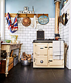Alter Holzofen und Vintage Tisch in Küche mit weißer Fliesenwand
