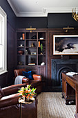 Fireplace, shelf and leather armchairs in the living room with black walls