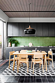 Dining area in front of a black kitchenette with green wall tiles