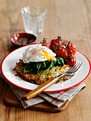A rösti topped with a fried egg, spinach and grilled vine tomatoes