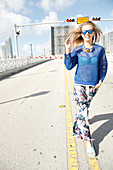 A young blonde woman wearing a net shirt and trousers with a floral print