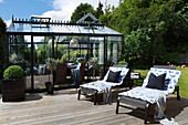 Two loungers on sunny wooden deck outside conservatory