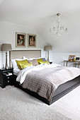 Double bed below chandelier in attic bedroom