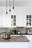 Pendant lamps above island counter in white country-house kitchen