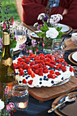 Cake with raspberries on table set for summer party