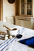 Pestle and mortar and eggs on rough linen cloth with three blue stripes