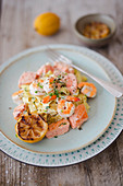 Tagliatelle with prawns, salmon, sour cream and grilled lemons on a wooden table