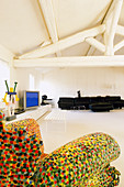 Multi-coloured armchair, TV cabinet and black sofa in bright attic living room