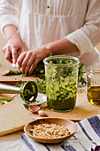 Herb pesto in a glass, surrounded by its ingredients