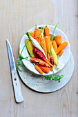 Various brightly coloured peeled carrots on a plate (top view)