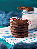 Stack of home made chocolate cookies with red twine over green background
